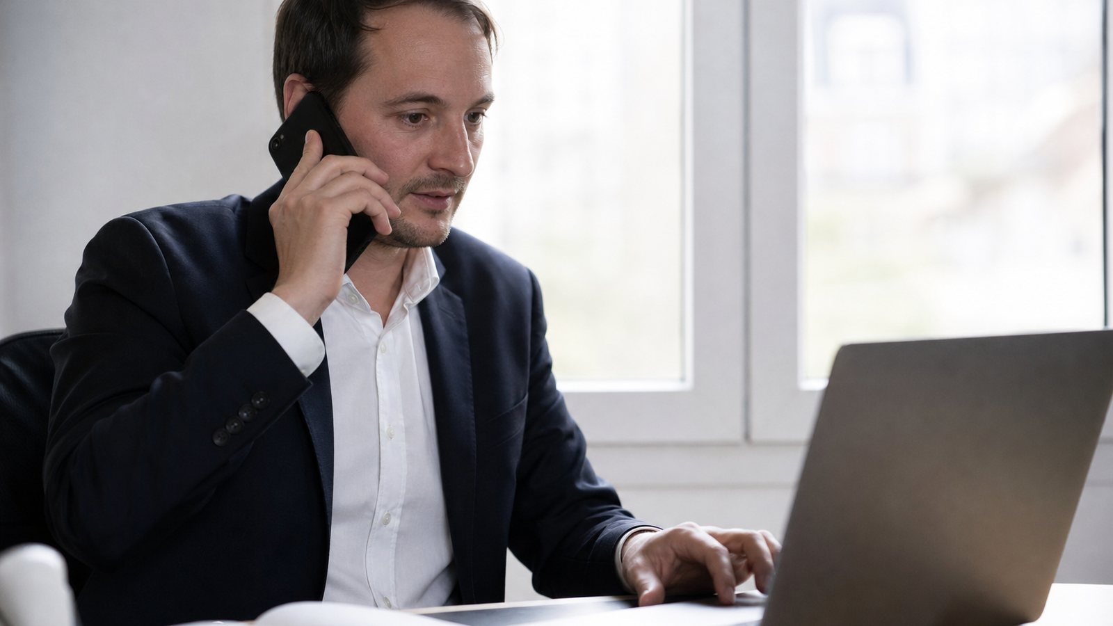 Gérant au téléphone avec une facture en main devant son ordinateur