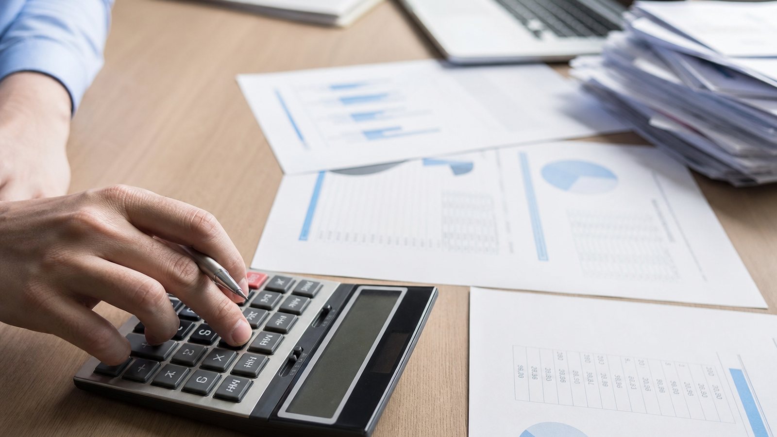 Gérant calculant les pénalités de retard d'une facture avec une calculatrice